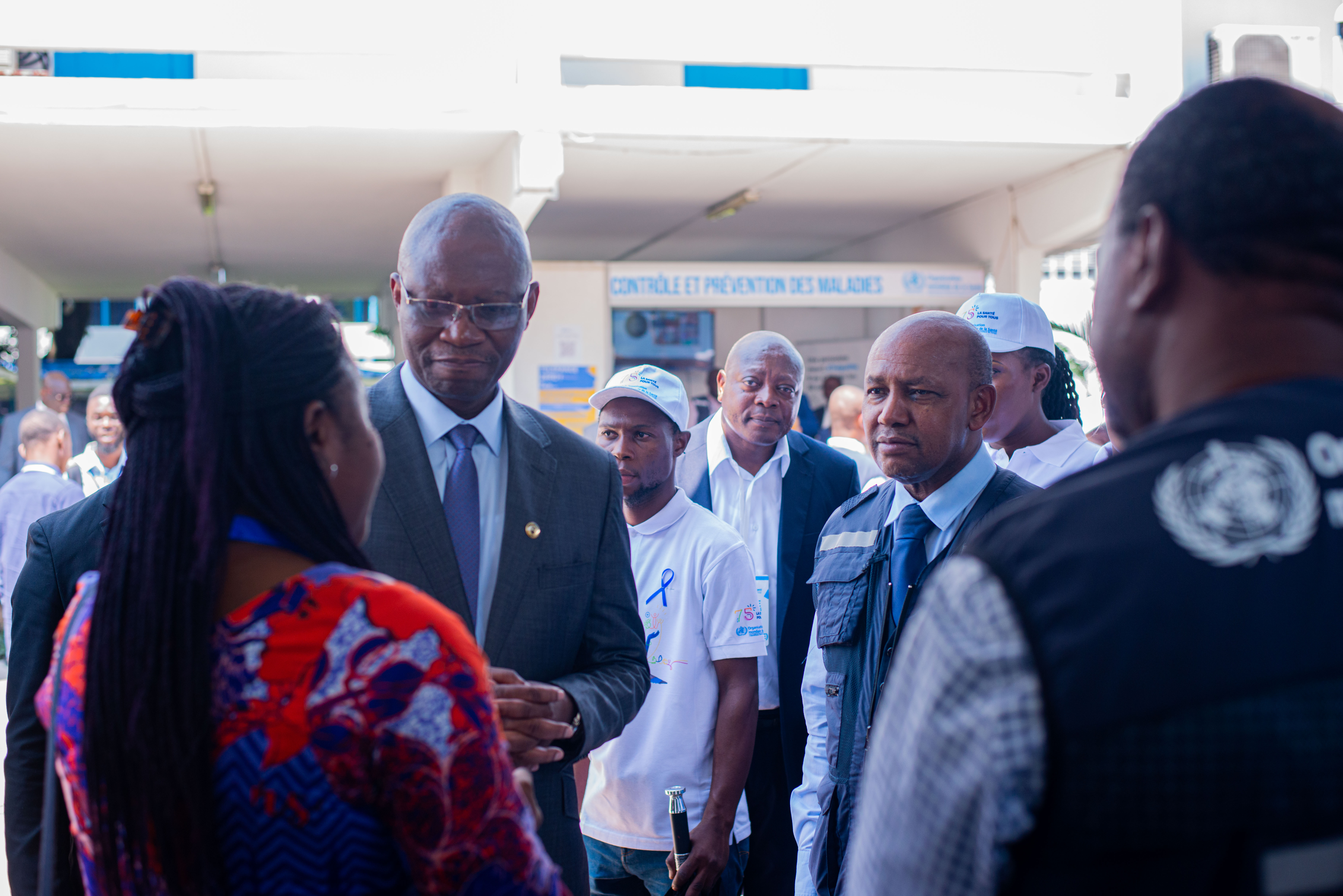 Le ministre de la Santé et le représentant de l'OMS écoutent les explications lors de la visite au stand du Renforcement du Système de Santé_HSS de l'OMS RDC