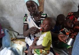 Woman giving PlumpyNut nutritional aid to her children in former Unity State