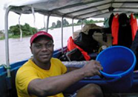 Daniel Umeh draining water from the boat after a downpour