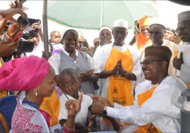 ED NPHCDA Dr Faisal Shuaib vaccinating the child of the Governor of Kaduna state while the Governor’s wife Hajiya Ummi El Rufai looks on.