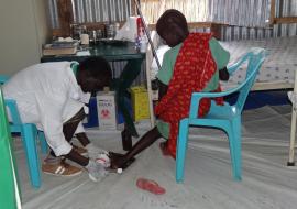 Health care worker dressing wound on a woman’s leg in Bentiu