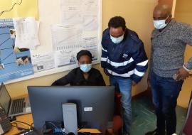 Mr S Kololo – MoHW/HSM (right) and Mr S Feleke – WHO Botswana (centre) observe the M&E Officer of Bobirwa DHMT practicing use of the docking station