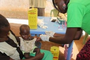 A laboratory technician draws blood from a child to test for malaria at an outreach post in Lologo Central Equatoria State, supported by WHO to mark World Malaria Day