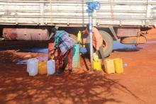 Individuals filling jerry cans from bore holes