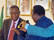 The WHO Representative in Nigeria, Dr Peter Eriki, Pins a STOP TB badge on the Hon Minister for Health, Prof B Osotimehin.