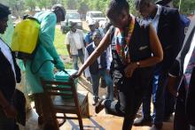 Le Dr Matshidiso Moeti se prêtant à l'exercice obligatoire de pulvérisation des pieds avant l'entrée dans la salle prévue de réunion de locale de coordination à Bikoro. OMS/EK