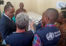 Le Ministre de la Santé écoutant les explications des logisticiens de l'OMS en rapport avec le réfrigérateur à vaccins anti Ebola destinés aux zones de santé touchées de l'Equateur. OMS/Eugene Kabambi