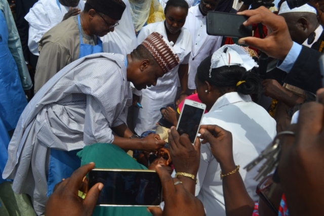 Taraba Deputy Governor Alhaji Haruna Manu immunizing a child at the flag off ceremony in Jalingo while the Minister of State for Health looks on
