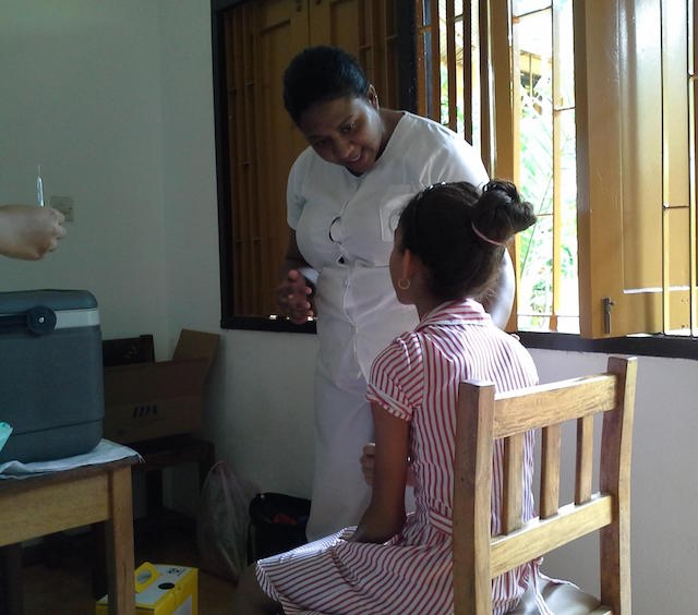 EPI nurse counsels a primary six student before administration of the vaccine at the school.jpg