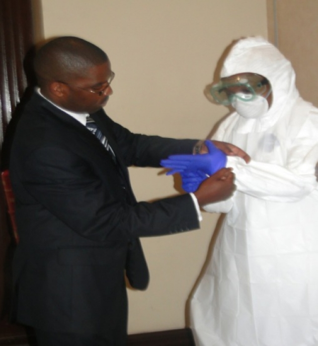 Victor Ofula of KEMRI Hemorrhagic Fever Laboratory demonstrates the donning of PPEs as participants of the TOT workshop try them out