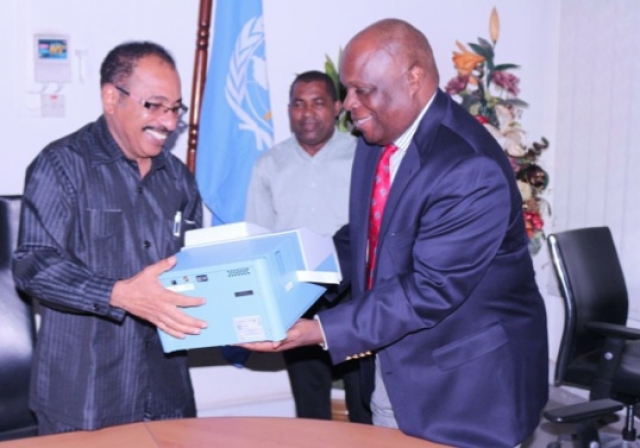 The WHO Representative, Dr. Rufaro Chatora handing over an ELISA Reader to the Minister for Health and Social Welfare, Hon. Dr Seif Rashid.