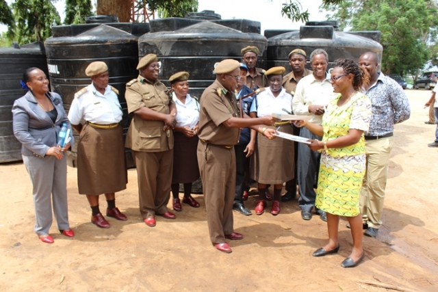WHO staff, Ms Rose Shija on behalf of the WHO Representative handing over the 4 water tanks to the Segerea prison management witnessed by Dar es Salaam Regional Health Officer and WHO staff.