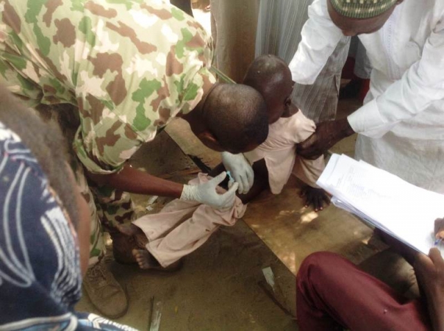 Military personnel vaccinating a child with IPV in Monguno IDP camp of Borno State