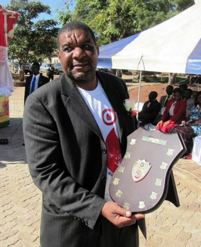 The Headmaster of John Tallach High School, national winners, showing off the shield won by the school