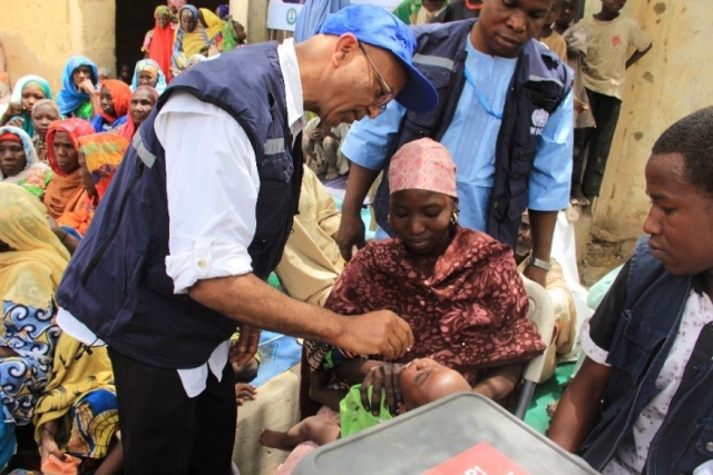 Dr Alemu administering oral polio vaccine to a child in a Borno IDP camp