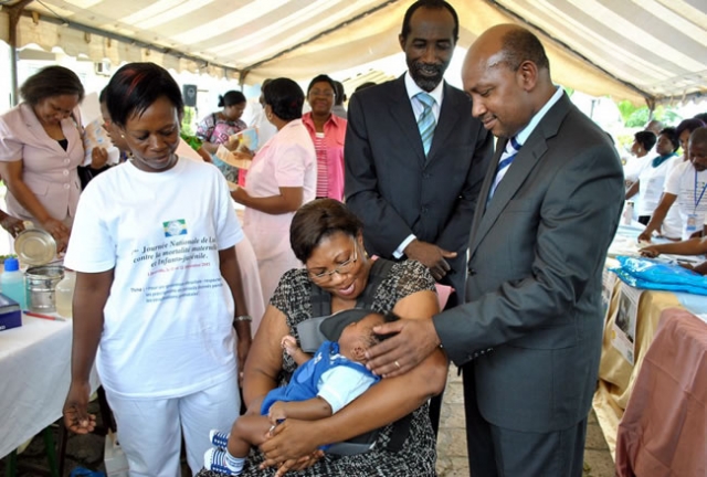 Le Représentant de l’OMS, Dr Boureima Sambo console un enfant en pleurs qui vient de se faire vacciner sous les regards bienveillants de la mère et du Dr Khouilla, DGS