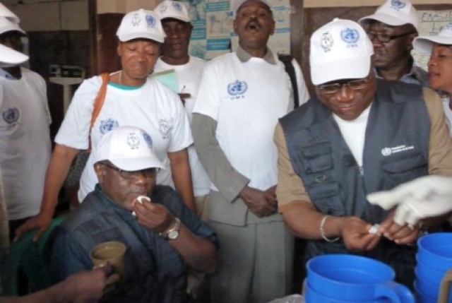 A droite: Le Ministre de la Santé après avoir donné le vaccin anti choléra au Représentant de l’OMS (assis)