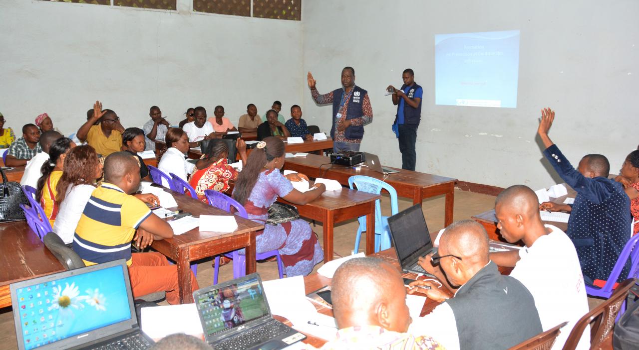 Le Dr Jean-Paul Ngandu, consultant de l'OMS spécialiste en prévention et contrôle de l'infection en pleine discussion avec les prestataires de la zone de santé de Bolenge dans une des salles du Centre de formation des cadres de l'EPSP Mbandaka . OMS/Eugene Kabambi