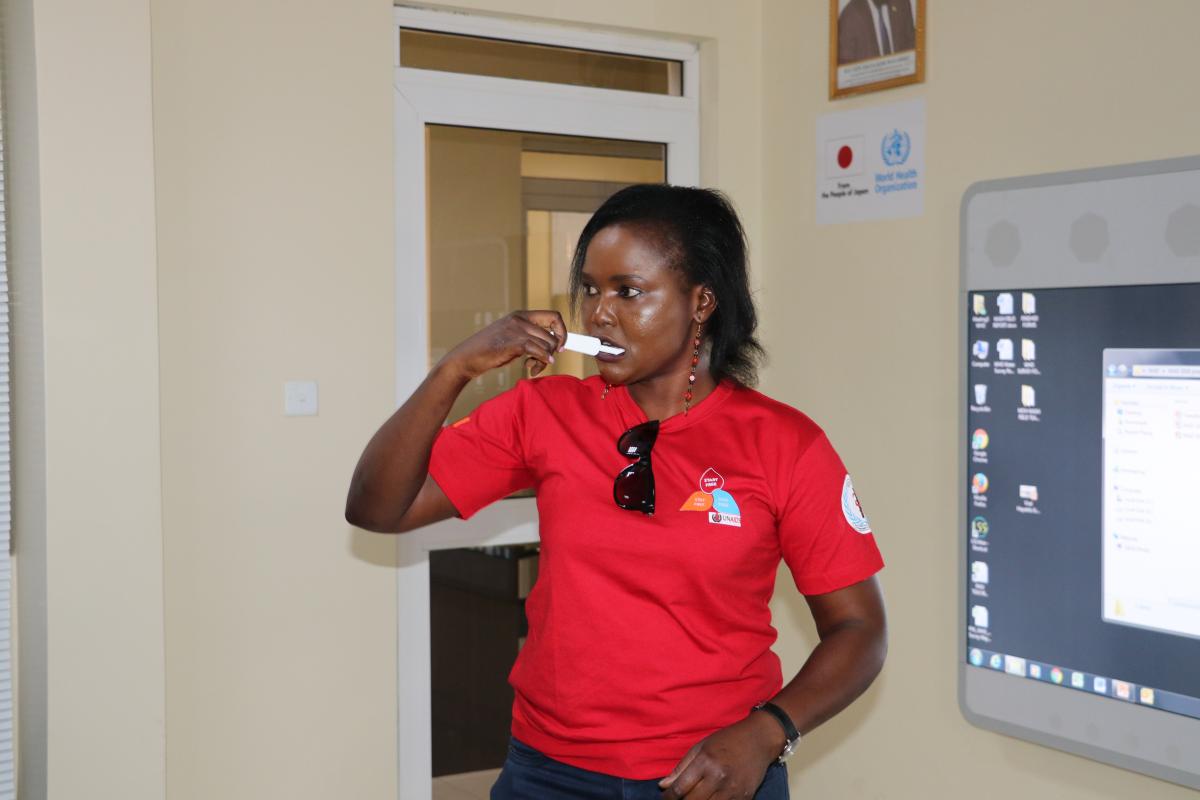 Ms Betty Araba of UNAIDS swabbing her mouth for an oral fluid sample for self-testing