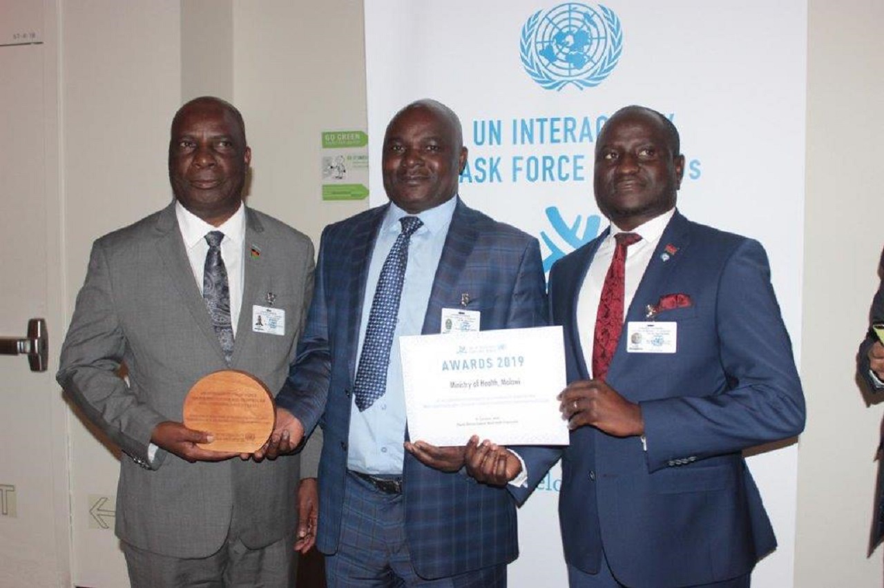 Honorable Minister of Health Jappie Mhango MP holding the UN Interagency Task Force award for NCD prevention and control