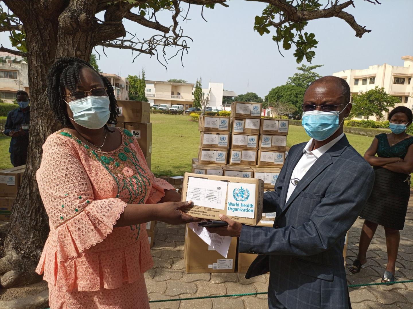 (De droite à gauche) Dr GLELE KAKAI Clément, Conseiller IHM, chargé des Urgences Sanitaires à l’OMS remettant un échantillon d’intrants sanitaires à Dr Armande Mathilda Eléonore GANDJETO, Directrice Adjointe du Cabinet du Ministère de la Santé