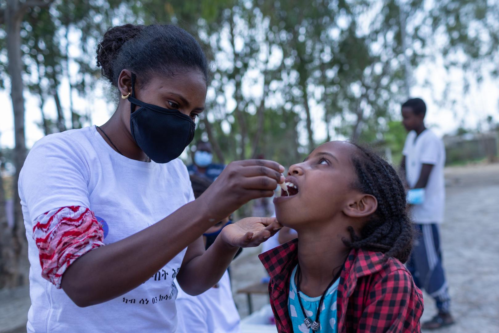 Selamawit administers oral cholera vaccine to a young girl at Yekatit 23 IDP camp in Mekelle