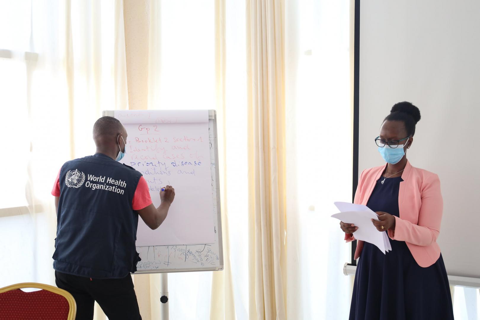 Dr. Alfred Rutagengwa (WHORwanda) and Mrs. Adeline Kabeja (RBC) organizing the IDSR review workshop participants into working groups.