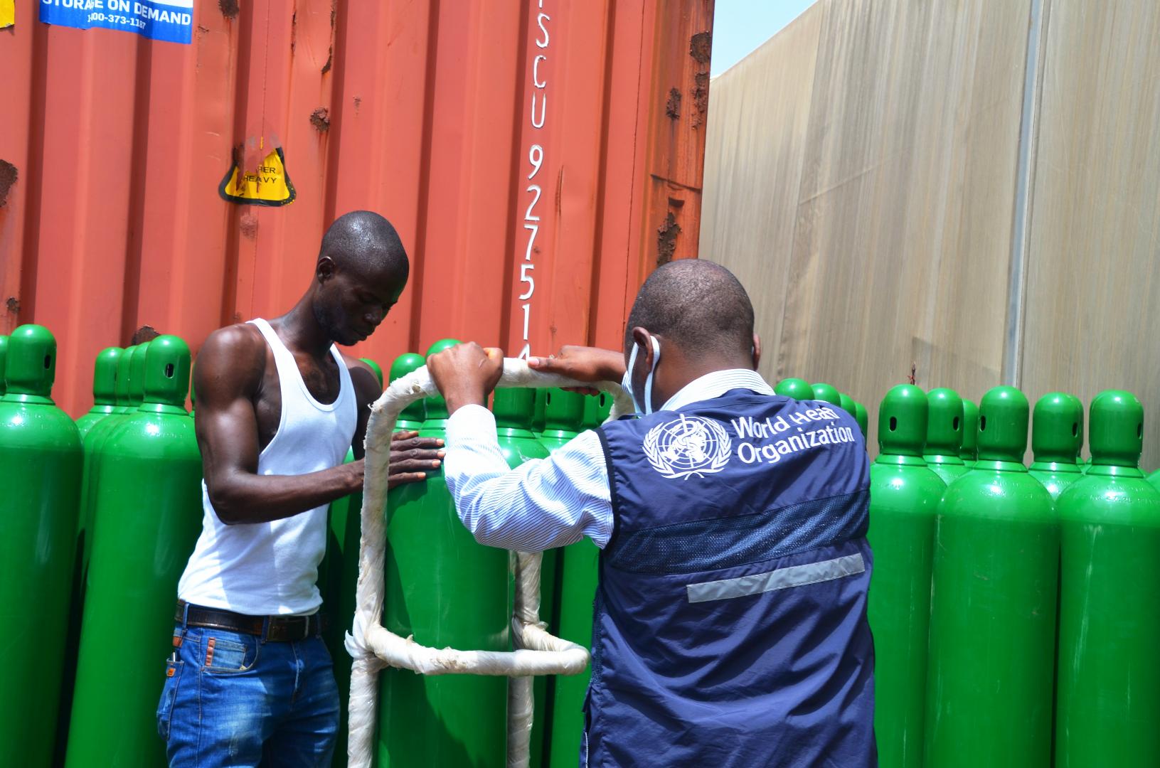 WHO staff supervising the offloading of oxygen cylinders at the Ministry of Health 