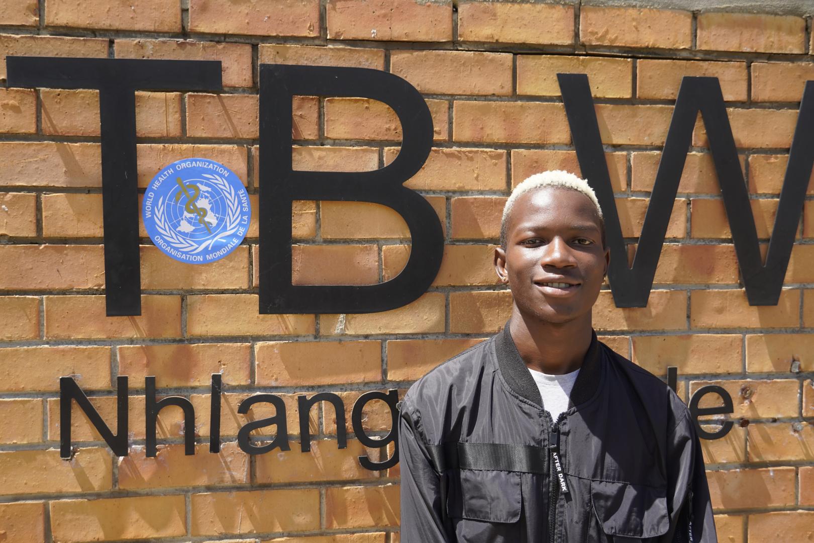 Siphephelosethu Ntjangase poses outside Nhlangano health center where he is receiving treatment