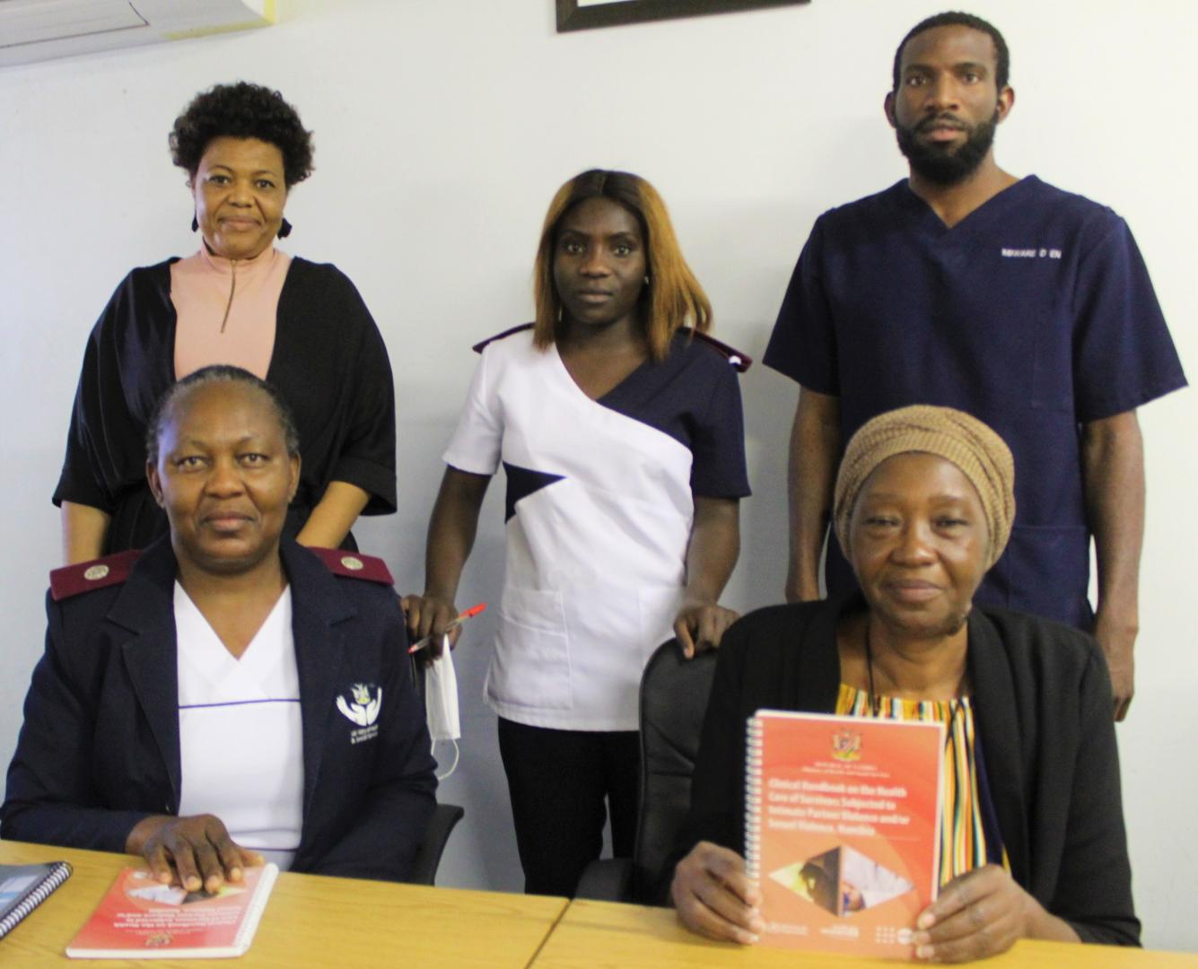 From left front: Justina Shoopala,Senior Registered Nurse at the Rundu State Hospital and Mrs  Angaleni Kangayi, Regional Chief Social Worker; Back row from left Florence Hangula, District Social Worker, a health worker and Mr. Mbware Ditmar Enrolled Nurse.  discussing the clinical handbook. 