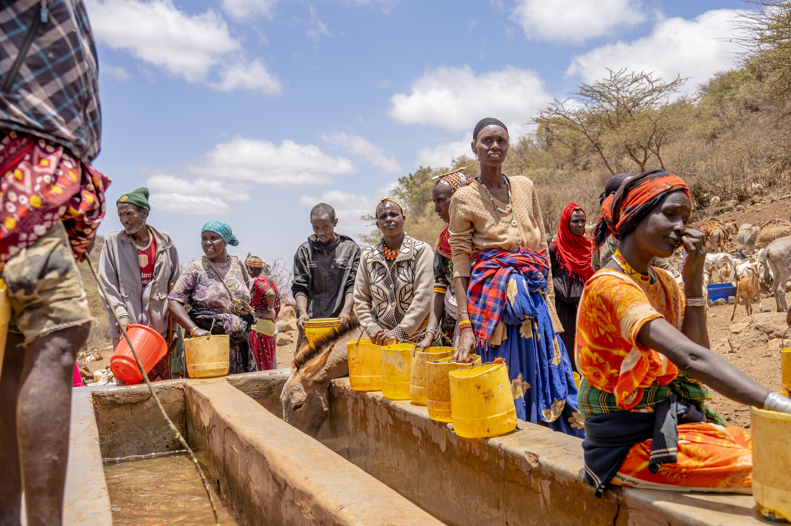 People wait in the midday sun for the water troughs to fill with water at Hula Hula Springs in Marsabit County, Kenya. With the ongoing drought in Marsabit, the spring is the only available water source for the whole community. 