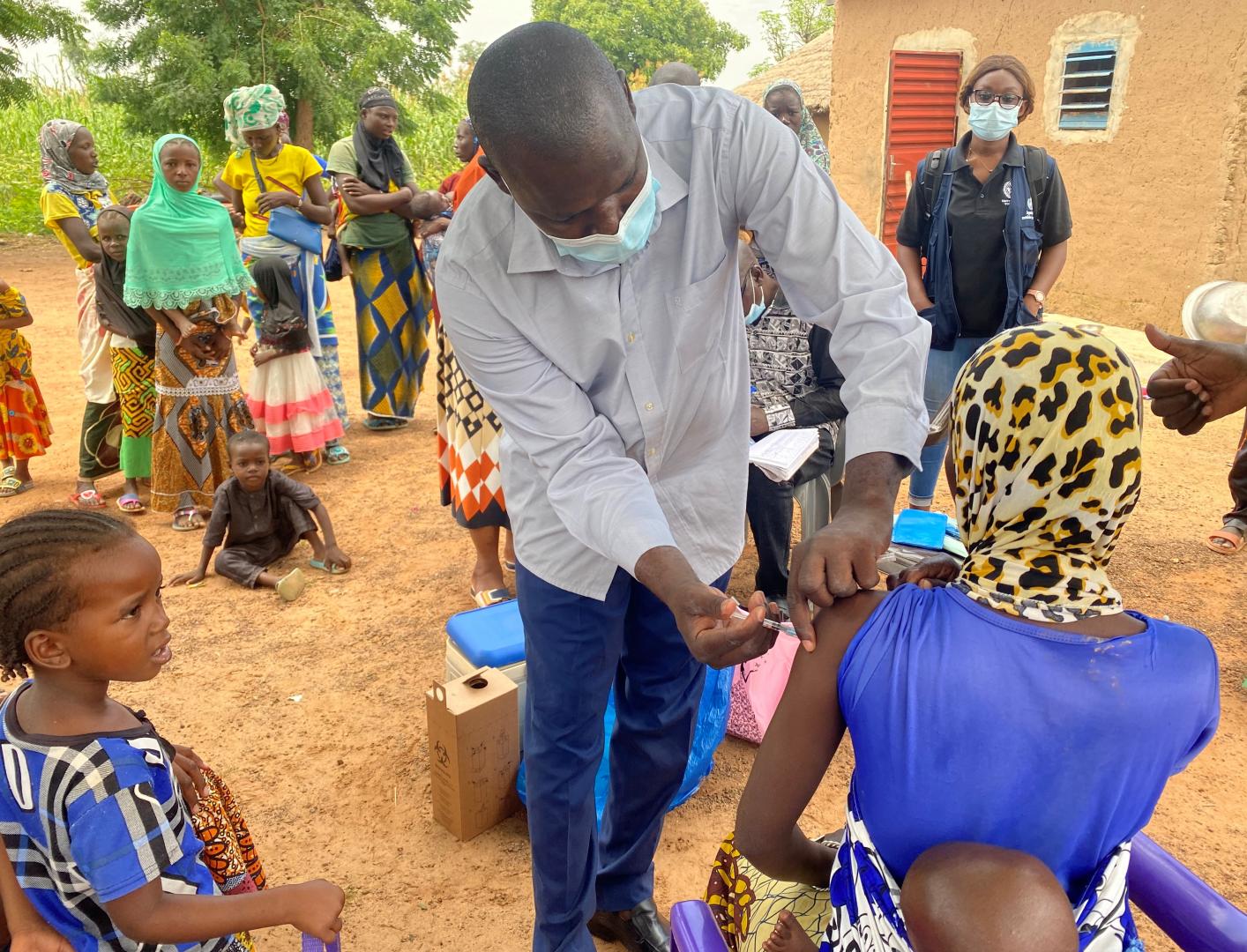 A man vaccinating a woman carrying a baby on her back