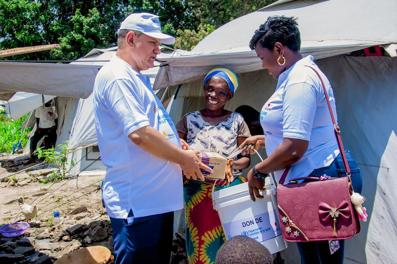 Le Représentant de l’OMS et la déléguée du MSPLS, remettant un kit d’hygiène à une femme du camp des déplacés de Maramvya.