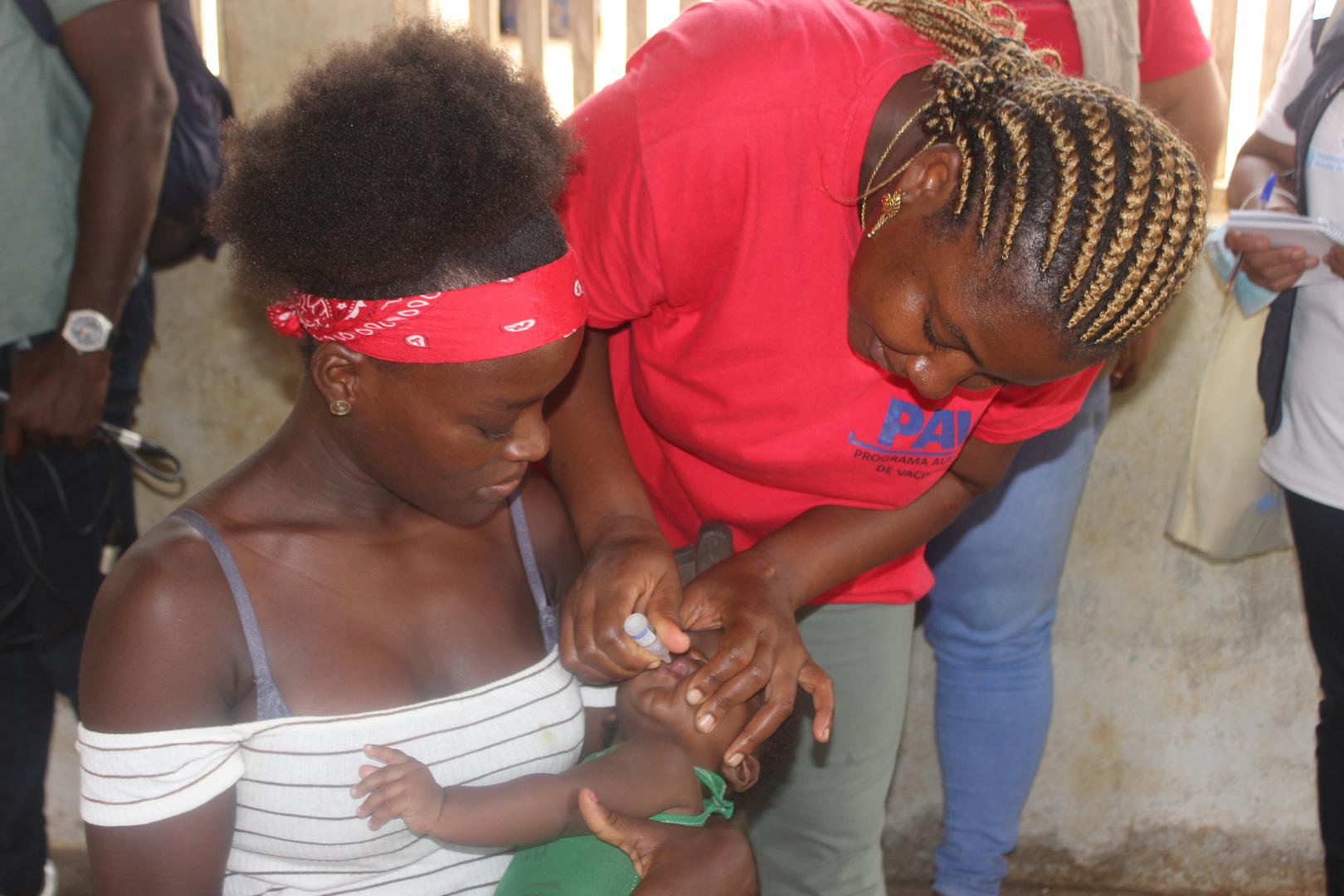 Uma crianca de seis meses recebendo a sua vacina de reforco