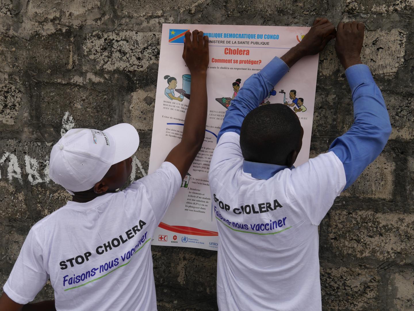 Health workers put up a poster on preventing cholera during an outbreak in Kinshasa in 2016. 