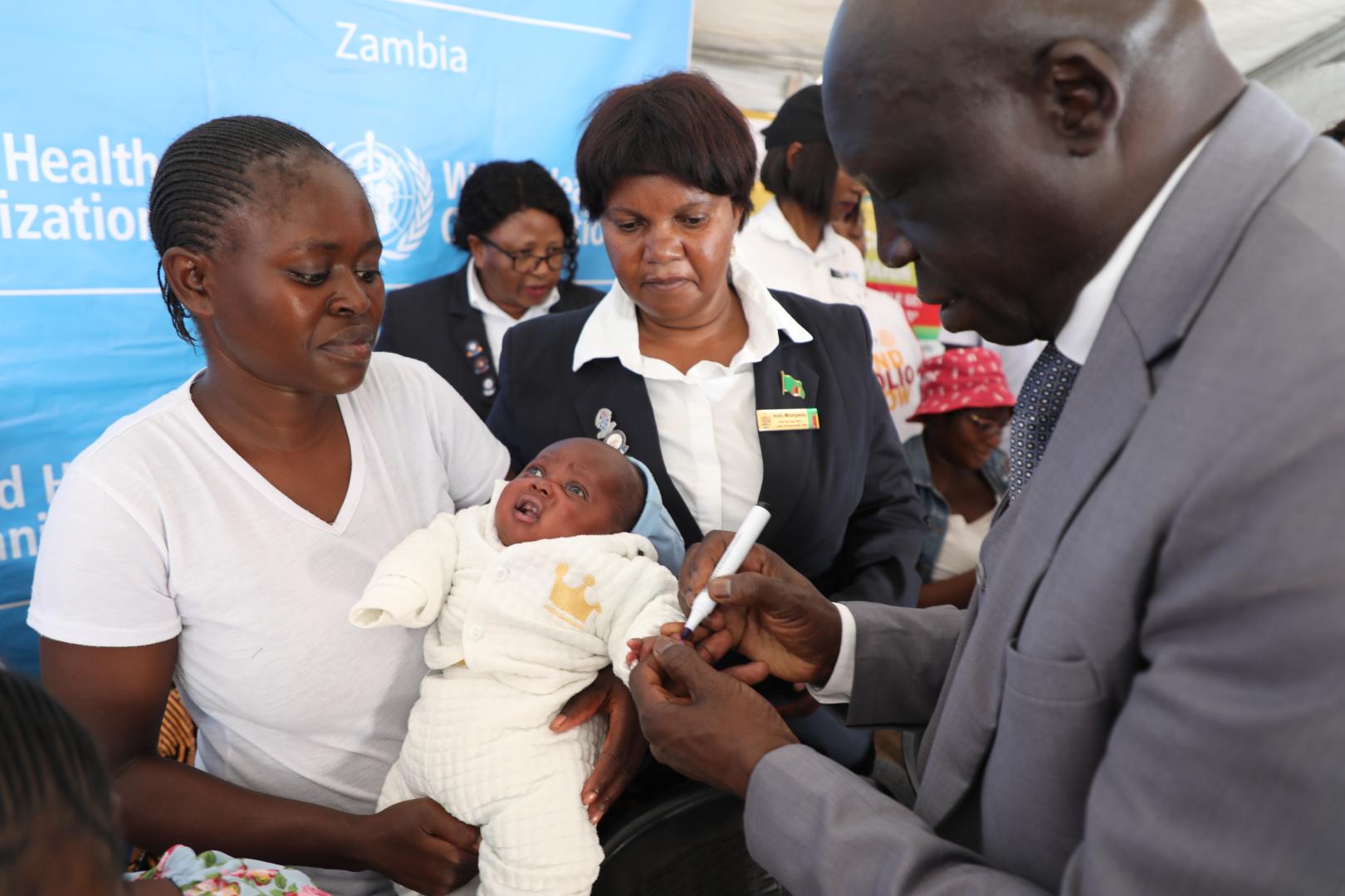 WHO Representative marking a vaccinated child