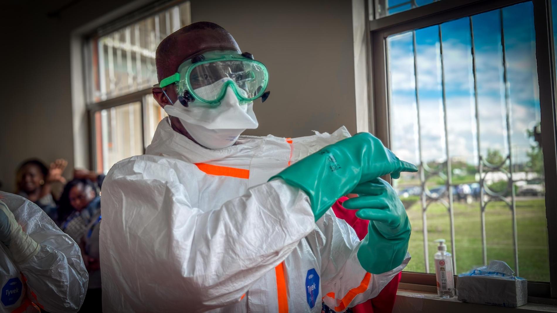 A health worker wearing personal protective equipment, including goggles, a face mask, a protective suit and gloves