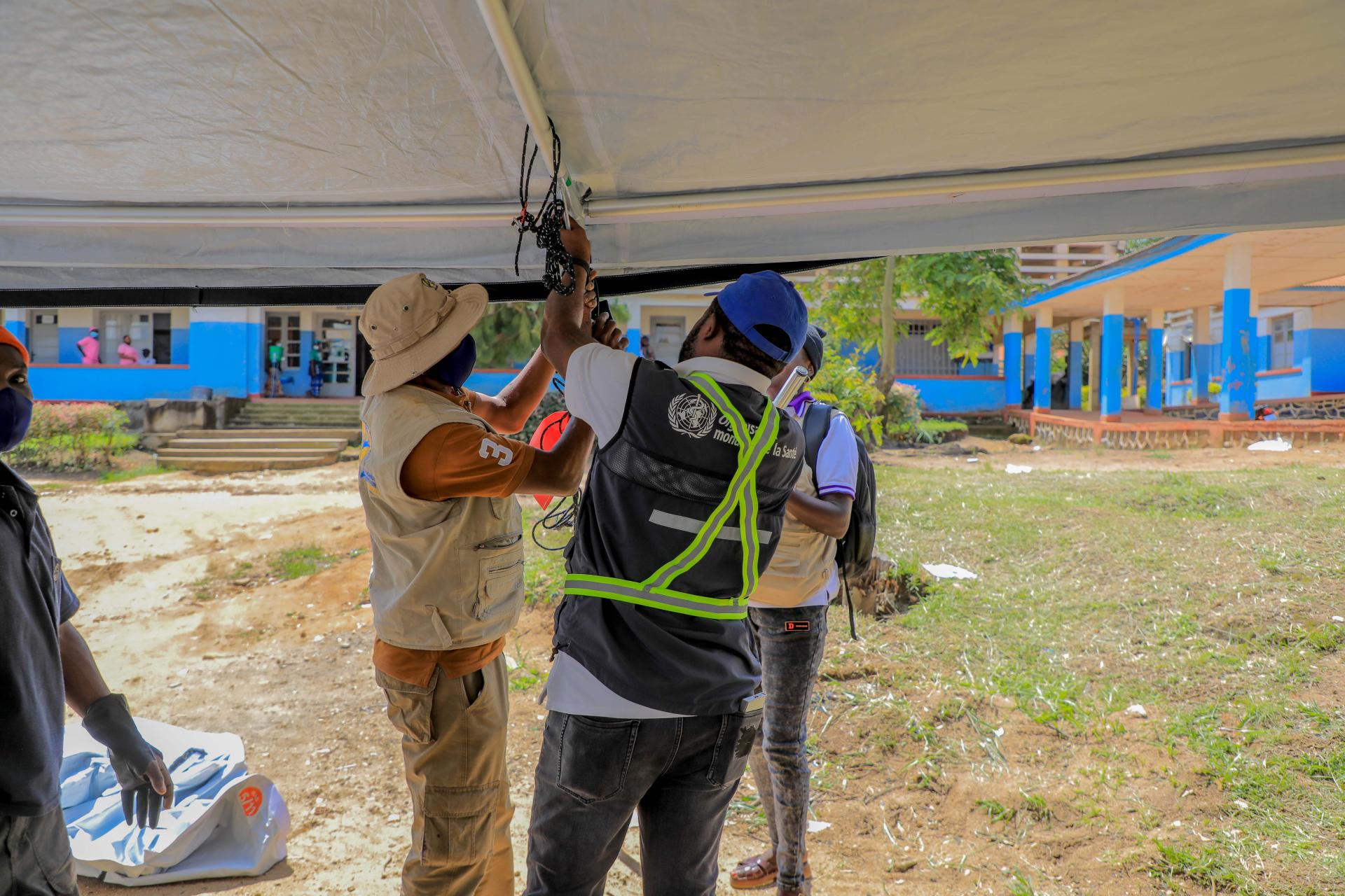 WHO field team installing a tent canopy at a health centre