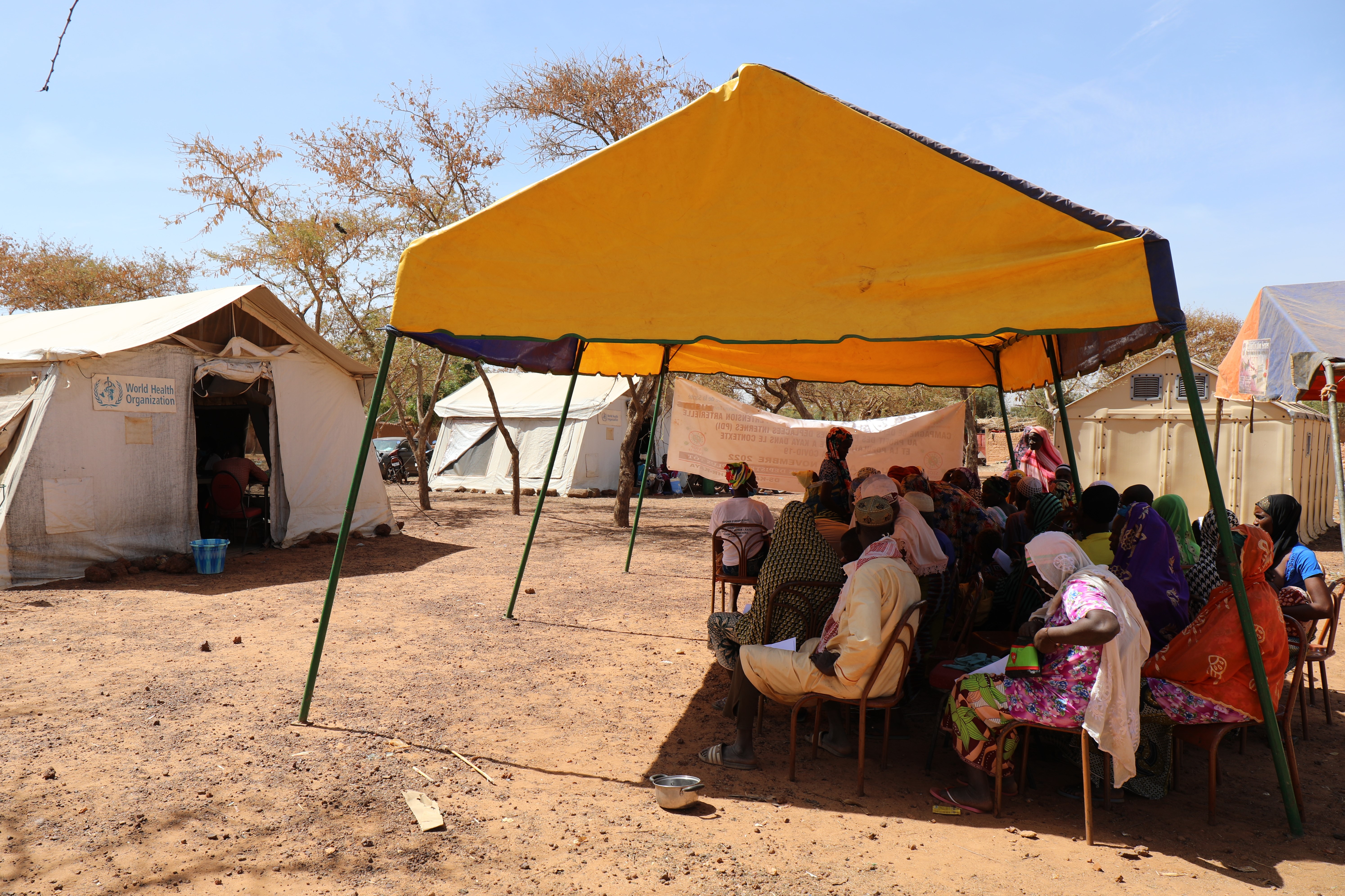 A group of person sitting under a tent