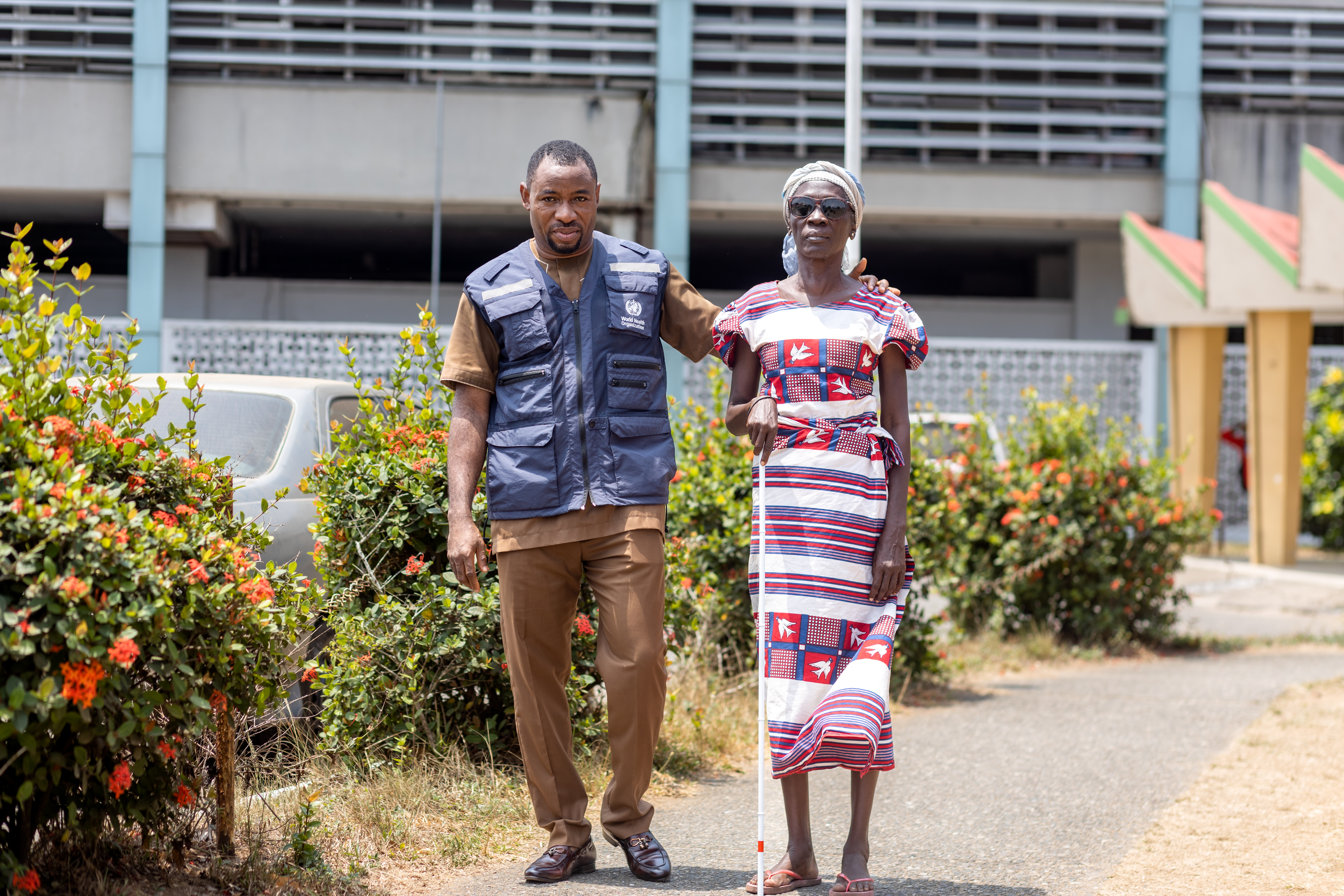 A beneficiary of WHO's donation standing with a WHO Staff after receiving her Cane