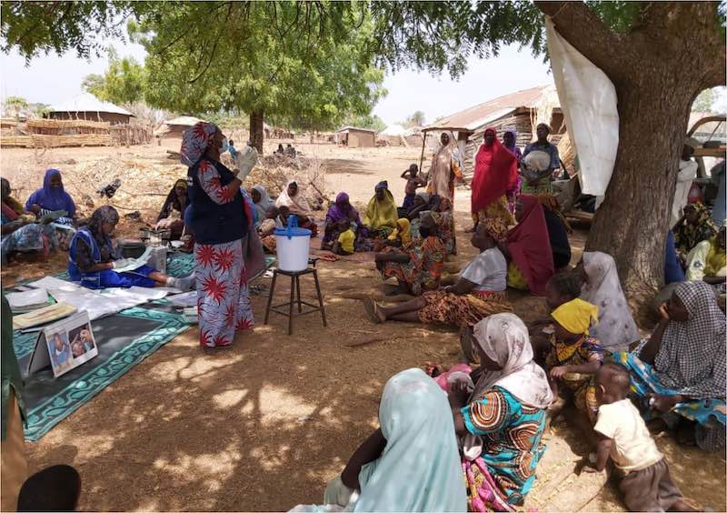 A WHO polio supervisor conducts a sensitization session on prevention of Covid-19 with community members and female leaders in a settlement in Borno State, Nigeria, April 2020