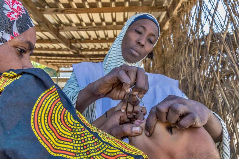 A vaccinator immunizes a child with the oral polio vaccine in Ngala, Nigeria, 2020 © Andrew Esiebo