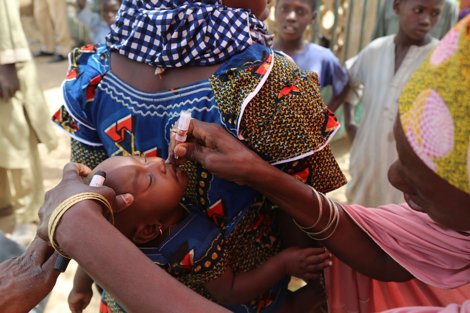 A mother's baby is vaccinated during a campaign held during a bustling market day, Sokoto State, Nigeria 2017 © WHO/J Swan