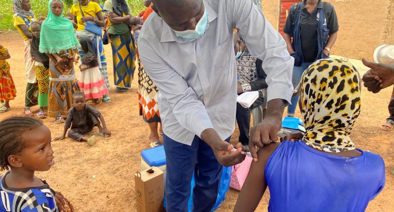 A man vaccinating a woman carrying a baby on her back