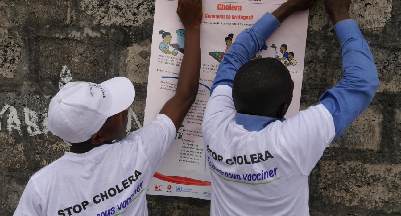 Health workers put up a poster on preventing cholera during an outbreak in Kinshasa in 2016. 