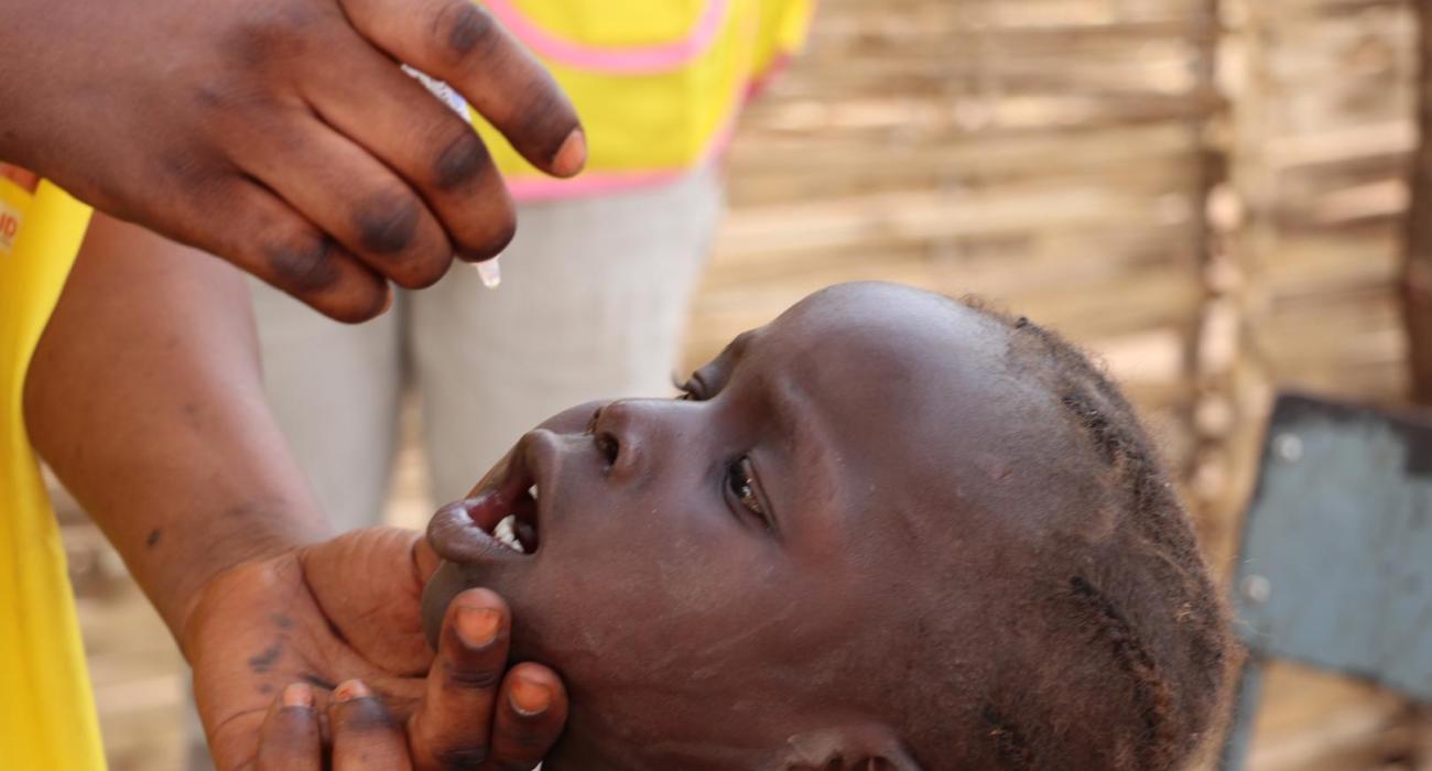 Healthcare workers administering the polio vaccine to a child as part of immunization efforts to protect children from poliovirus.