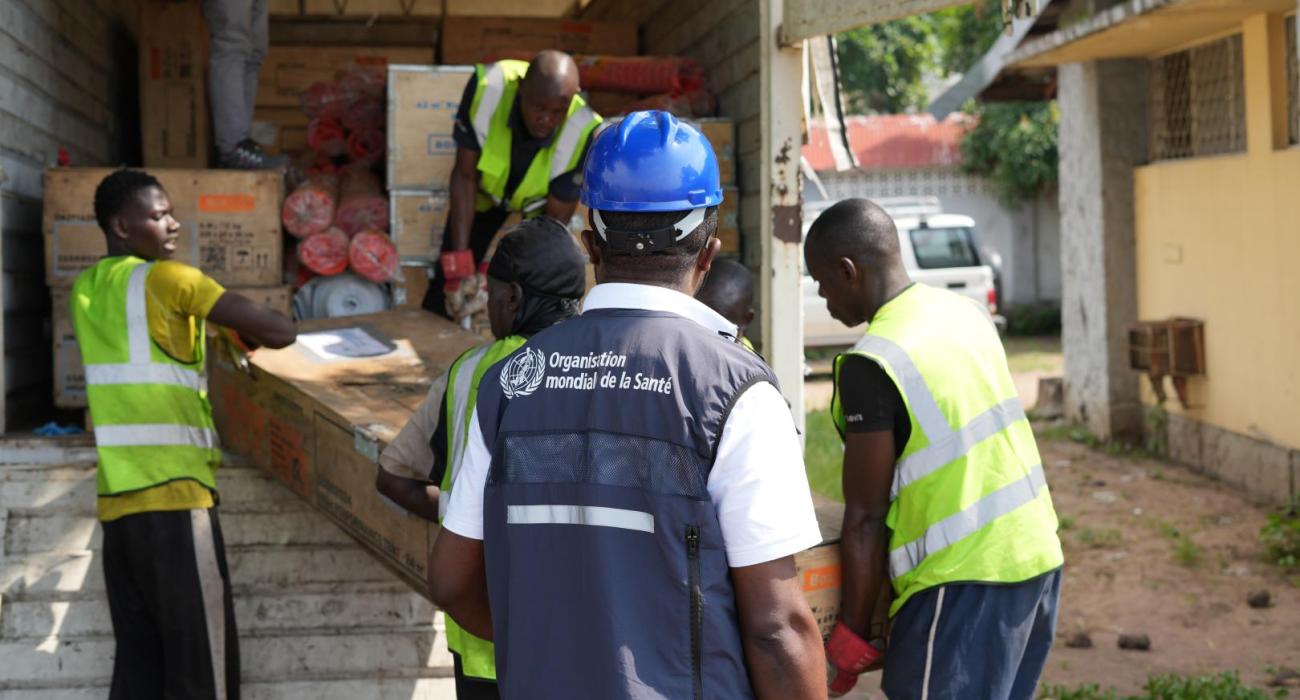 Déchargement des fournitures médicales de l’OMS destinées à l’installation d’une unité de traitement du choléra à proximité de l’hôpital de la Rive, dans la zone de santé de Binza Ozone, à l’ouest de Kinshasa. Cette initiative vise à renforcer la prise en charge des patients touchés par la maladie. – OMS/Joël Lumbala