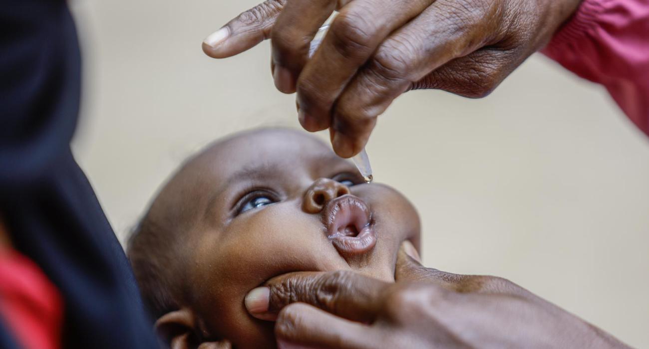 A baby receives oral polio vaccine drops during a childhood immunization activity.