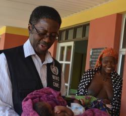 Dr Sagoe-Moses holding the newborn as the mother looks on