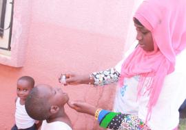 A vaccinator administering the polio vaccine to a child